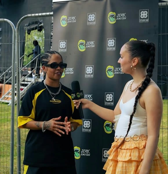 An artist interview in front of the Jerk Junction backdrop at Manchester Carnival